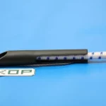 A blue and white braided rope from the 12″ Scaffold Bungees set passes through a black plastic clip against a blue background. The letters "KOP" are printed on a small white rectangle nearby.