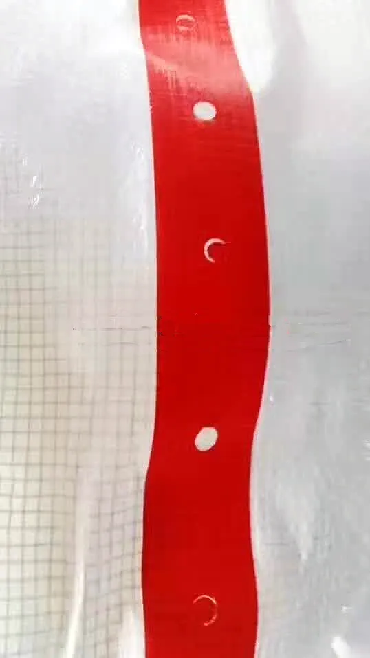 Close-up of the Clear String Reinforced Poly Tarps – 7 oz FR SCAFFOLD SHEETING, showcasing a translucent plastic sheet with a red vertical stripe featuring small round holes at regular intervals and a faint grid pattern.