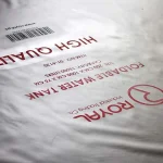 Close-up of a white plastic sheet showcasing red text. The text includes phrases such as "HIGH QUALITY" and "FOLDABLE WATER TANK," along with a product barcode and the brand name "ROYAL." This item is labeled as Custom Printed Tarps.