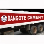 A truck outfitted with a custom printed tarp in red and white, showcasing the text "Dangote Cement" alongside the company's logo.