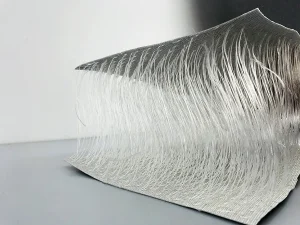 Close-up of a piece of Double Wall Fabric, Drop Stitch Tarpaulin with multiple fine threads extending outward, displayed on a light-colored surface against a plain background.