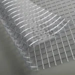 Close-up of FR SCAFFOLD SHEETING-10oz, partially lifted at the corner, revealing its transparent grid pattern on a flat surface.