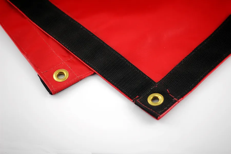 Close-up of a Lumber Tarp with Flap for Flatbed Truck and Trailer – 8′ Drop, featuring a red surface with black reinforced edges and brass grommets at the corners, laid out on a white surface.