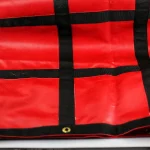 A red Lumber Tarp with Flap for Flatbed Truck and Trailer – 8′ Drop, featuring black stripes and brass grommets.