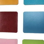 Close-up of a sample sheet displaying various textured, colored squares of PVC Floor Vinyl, with prominent red and blue squares centered among other colors.